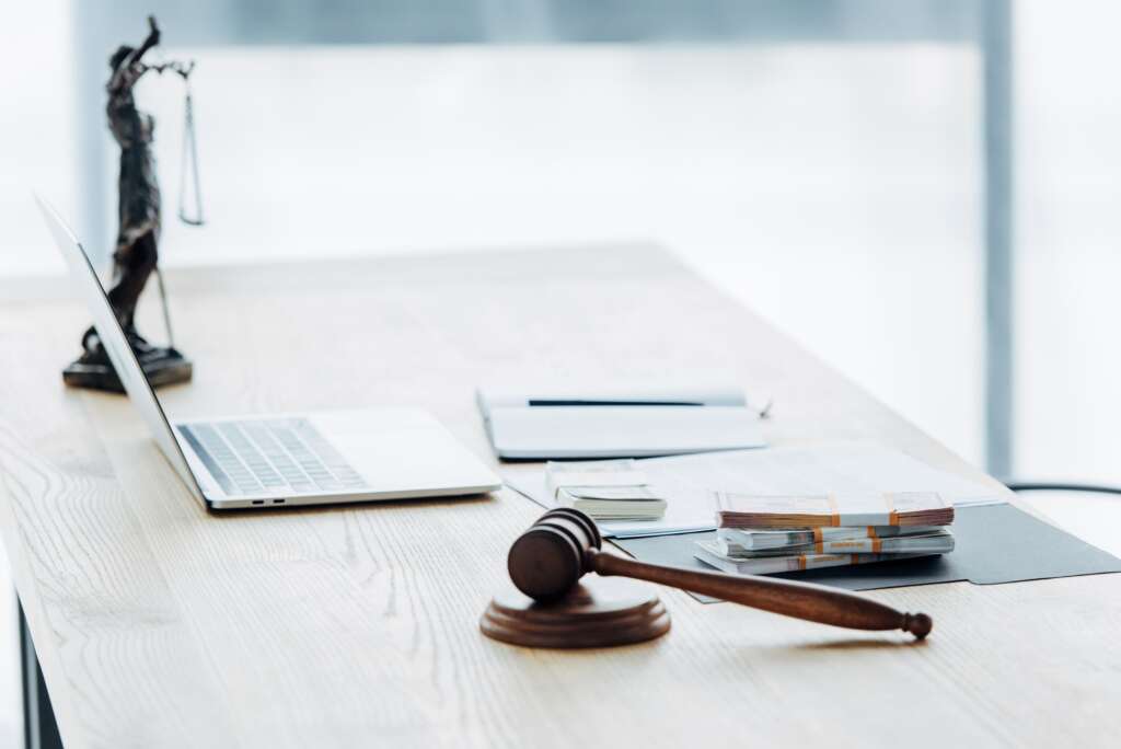 selective focus of money on folder near statuette of justice